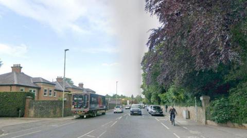 A Google streetview screenshot of Woodland Road in Darlington. The road is busy with traffic and a cyclist is on a cycle path on one side.