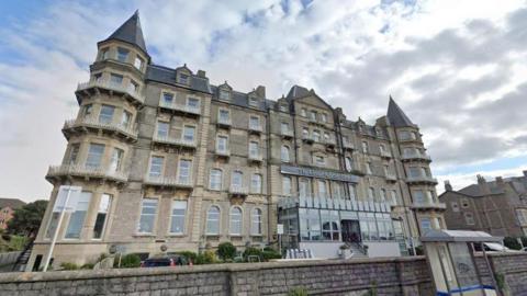 A Google Maps screengrab of the Grand Atlantic Hotel, a grey, five-storey Victorian building with pointy turrets and a glass entrance hall. 