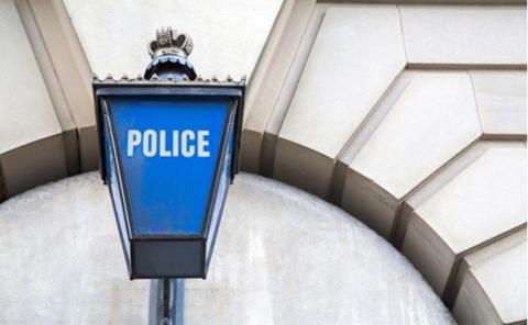 A close-up of a blue lamp on a building with the word "police" on it.