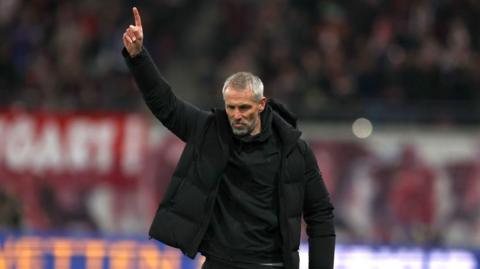 Marco Rose stands with one arm aloft