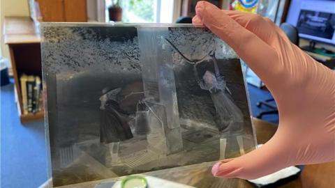 A hand in a pink glove holding a photograph