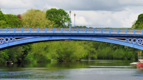 The bridge is blue and spans the River Severn. Two lanterns are visible on columns in the middle of the bridge.