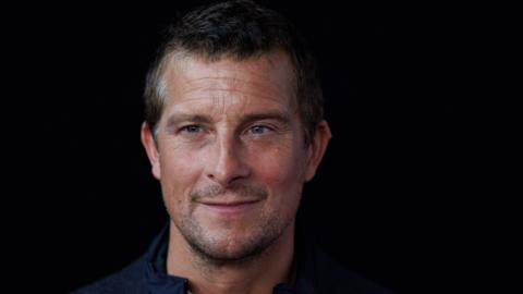Bear Grylls smiling in front of black background