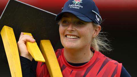 Sophie Ecclestone smiles while carrying stumps