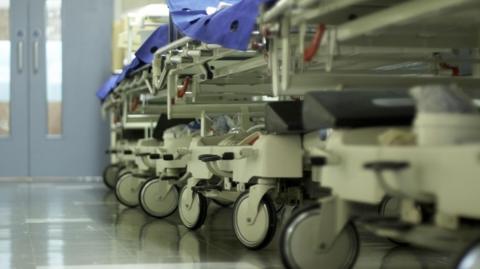 A hospital corridor with gurneys lined up on the side.