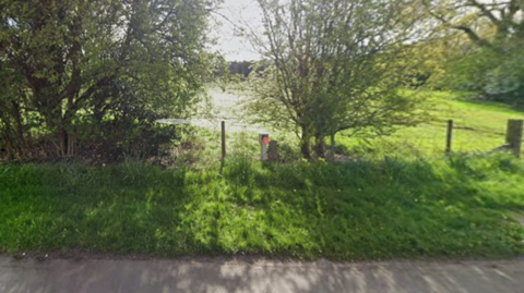 Open field behind a hedgerow