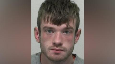 Mugshot of Wilkinson. He has short stubble and short thick dark hair.