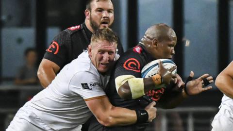 Bongi Mbonambi of the Cell C Sharks is tackled by Bradley Davies