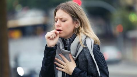 Person coughing in street