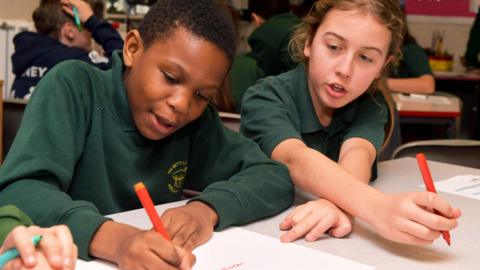 Two children in school uniform, writing