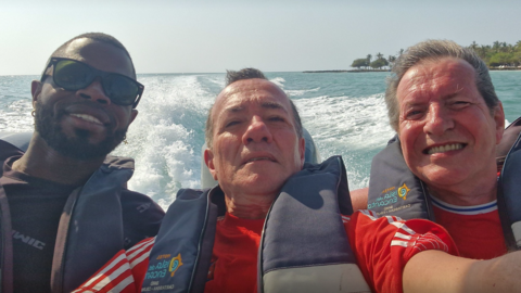 L-R Yostin Andres Mosquera, Albert Alfonso and Paul Longworth. They are shown smiling at a camera in a selfie, all wearing life jackets as they sit at the back of a speedboat.