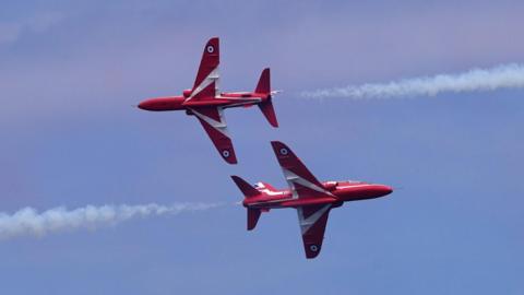 Two Red Arrows jets passing within feet of each other, flying in opposite directions