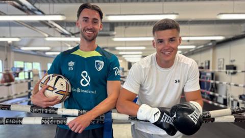 Owen and Taylor Bevan pose for a photo while standing inside a boxing ring