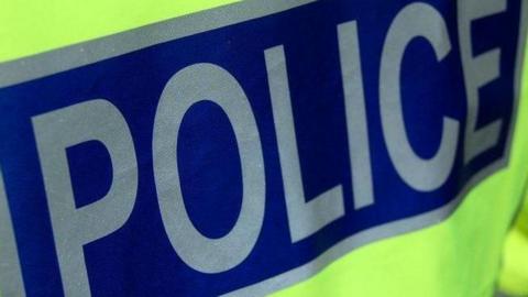 Police officer's jacket with the word police in silver letters on a dark blue background.