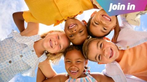 Five children linking arms and looking down into the camera. 