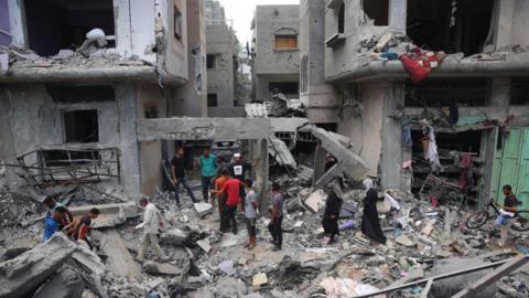 Palestinian children inspect the rubble of destroyed buildings after an Israeli hostage rescue operation in Nuseirat refugee camp, in central Gaza (9 June 2024)