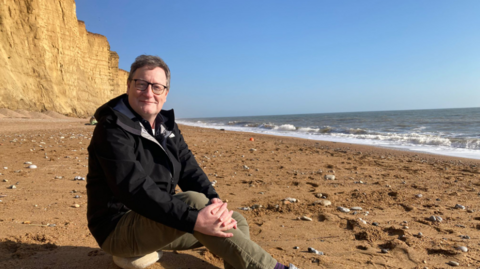Chris Chibnall sat on East Beach in West Bay, where he thought up his award-winning TV series, Broadchurch.