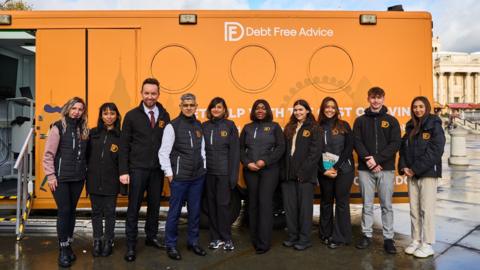 Sadiq Khan and Debt Free Advice staff in front of bus