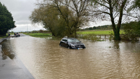 A black car stuck in flood water on the A417