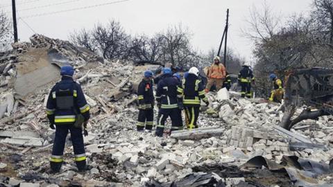 Emergency workers climb across a huge pile of rubble