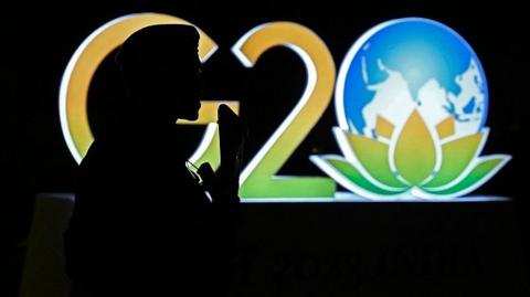 An armed security personnel stands guard near a G20 India summit logo installed along a street in New Delhi on September 6, 2023, ahead of its commencement.