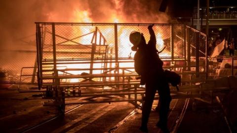 A protester throws a bottle onto a burning barricade in Hong Kong. Photo: 31 August 2019