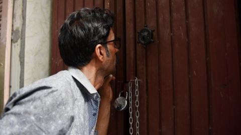 A man peeps inside the house where 11 members of a family allegedly committed suicide on 2 July in Delhi.