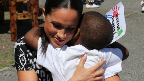 Meghan shares a hug with a youngster