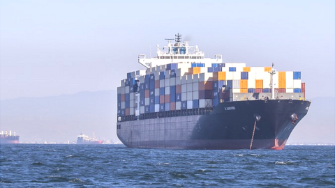 Two full container ships, and two more in the background, in the water outside Los Angeles ports