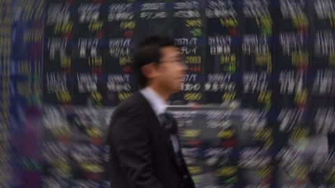 Man walking past stock boards in Tokyo