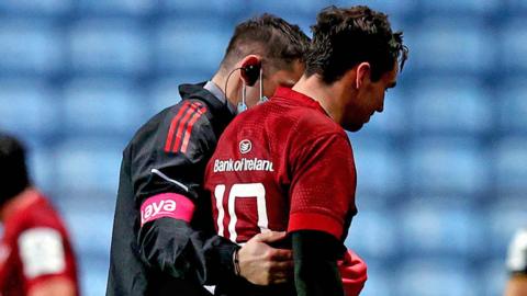 Joey Carbery is helped off the pitch by a member of Munster's medical team