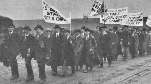 Blind marchers with campaign banners