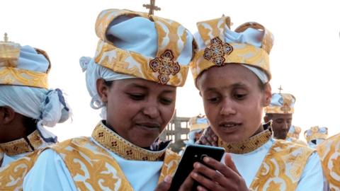 Ethiopian Orthodox Christians use smartphones during a religious celebration in Addis Ababa - 2019