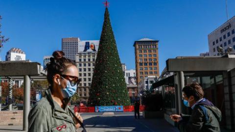 People walk through a quiet Union Square, past a Christmas tree, in San Francisco, California on 1 December 2020