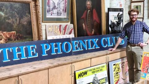 Auctioneer James Warren with the Phoenix Club sign