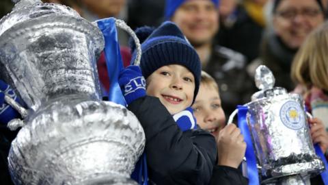Young Leicester City supporters hold tin foil FA Cups