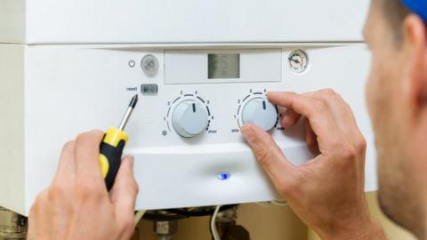 Worker sets up central gas heating boiler at home