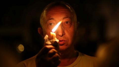 A man holds a candle outside the Instituto Politecnico, a technical high school, where the five Argentine citizens who were killed in the truck attack in New York on October 31 went to school, in Rosario, Argentina November 1, 2017.