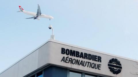 A plane flies over a Bombardier plant in Montreal, Quebec, Canada