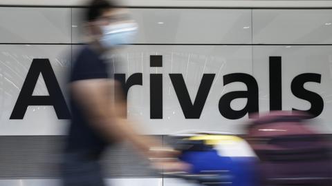 A traveler exits through the International Arrivals gate at Heathrow Airport on August 7, 2021