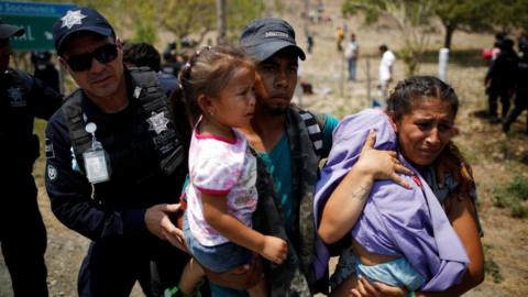 A family of Central American migrants is detained by Federal Police during a raid on their journey towards the United States