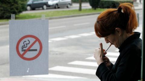 Image shows woman smoking outside a bar in Spain