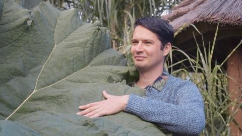 A man and a large leaf