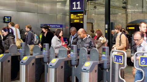 Passengers walking through ticket barriers at a train station