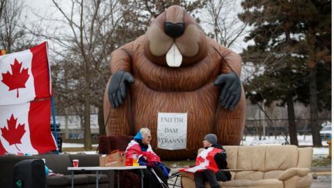 Protestors and supporters sit at a blockade at the foot of the Ambassador Bridge