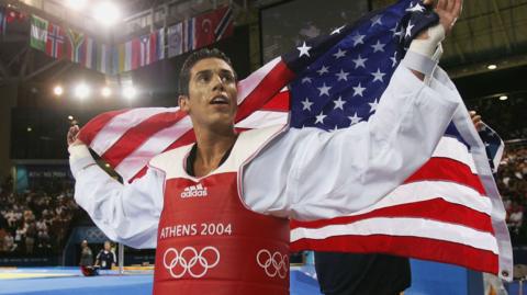 Steven Lopez holding the US flag at the 2004 Olympics