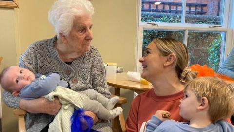 Bernice holding a child with a mother and her child