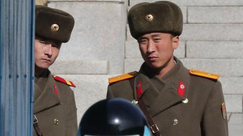 North Korean soldiers look on as a South Korea soldier (bottom) stands guard at the joint security area during a visit of Australian Foreign Minister Julie Bishop at the truce village of Panmunjom in the Demilitarized zone (DMZ) dividing the two Koreas on 18 February 2017.