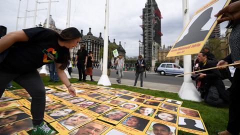 Campaigners display photos of the victims of the Grenfell Tower fire outside the Houses of Parliament