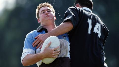 Male rugby player being caught in a tackle